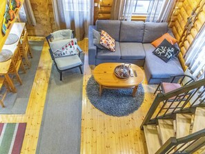 A cozy cabin interior with a wooden floor, a sofa set, a dining table, and a staircase. - Antura b by Interhome (Pelkosenniemi)