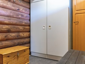 Una habitación con pared de madera, un armario blanco y un banco de madera.