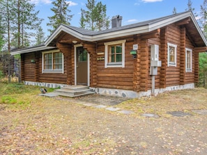 A log cabin with a front porch, a chimney, and a stone foundation. - Pyhä-rasti by Interhome (Pelkosenniemi)