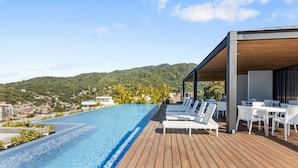 A rooftop infinity pool with wooden decking and white lounge chairs, overlooking a hilly landscape. - 2BD 2Bath Oceanview The Palm on the Tree Unit 10  2BD Condo for rent in Old Town (Puerto Vallarta)