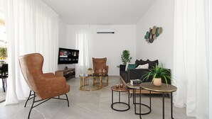 A modern living room with a brown leather chair, a black sofa, and a small round table with a plant.