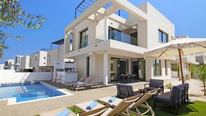 A modern two-story house with a swimming pool, outdoor seating, and a well-maintained garden.