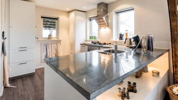 Eine moderne Küche mit einer Granit-Arbeitsplatte, Edelstahlgeräten und einem Fenster für natürliches Licht.