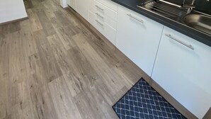 Een moderne keuken met witte kasten, een zwart aanrecht en een houten vloer.