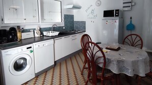 A compact kitchen with a washing machine, a sink, a dining table with chairs, and a microwave. - Quiet house near Domino market (Saint-Georges-d'Oléron)