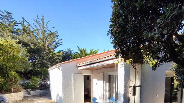 A small house with a patio, a table with chairs, and a stone wall. - Quiet house near Domino market (Saint-Georges-d'Oléron)