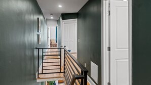 A hallway with dark walls, a wooden staircase, and white doors. - Spacious 3BR Near Art Museum | Patio | Gameroom (Philadelphia)
