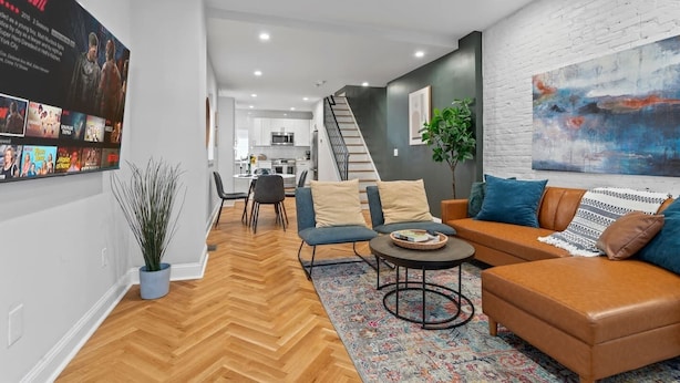A modern living room with a herringbone floor, a sofa set, a coffee table, and a painting on the wall. - Spacious 3BR Near Art Museum | Patio | Gameroom (Philadelphia)
