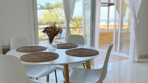 Zona pranzo con tavolo bianco, quattro sedie bianche e sottopiatti di fibra.