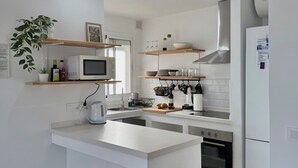 Una cucina moderna con mobili bianchi, un'isola centrale, un forno a microonde, un fornello e un frigorifero.