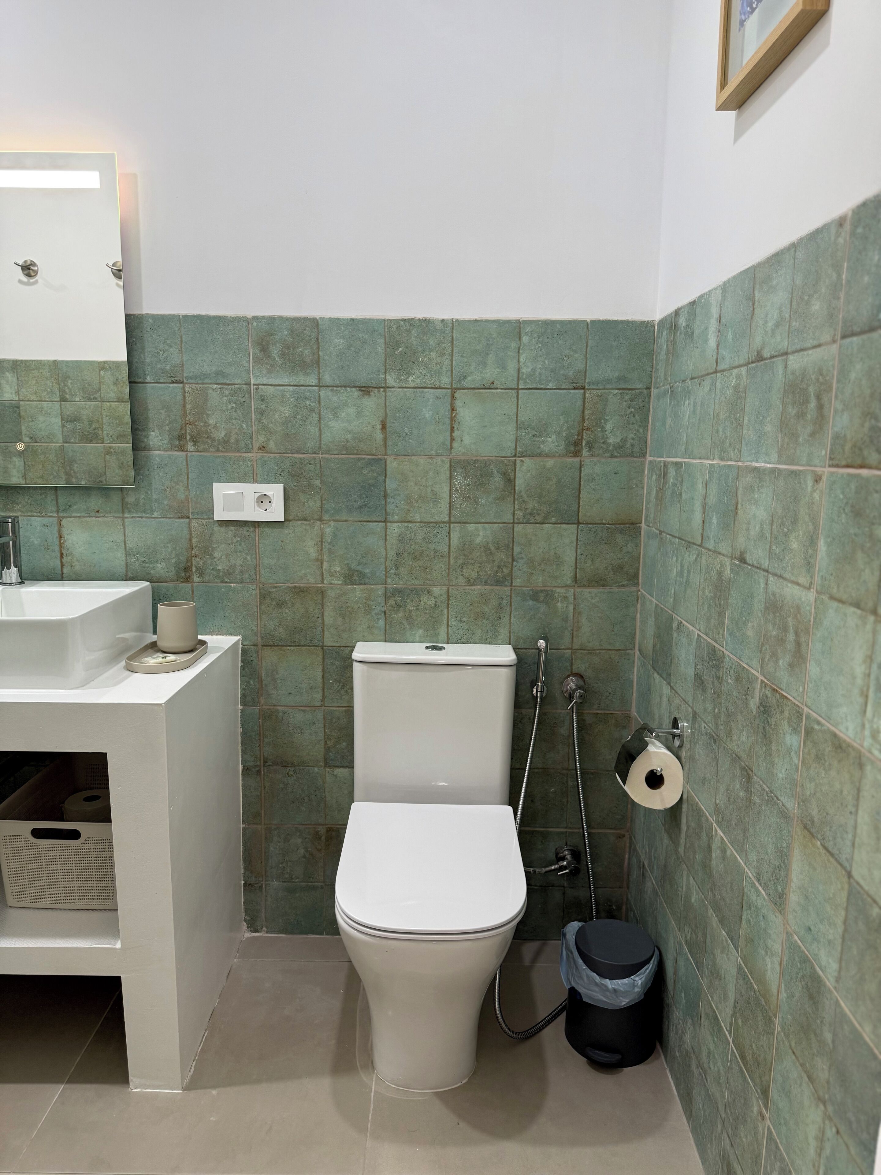 A compact bathroom with a white toilet, a sink, and a mirror.