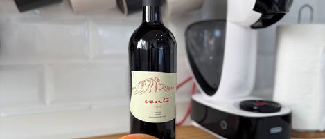 Een aanrecht met een fles wijn, een mango, bananen en chocoladerepen.