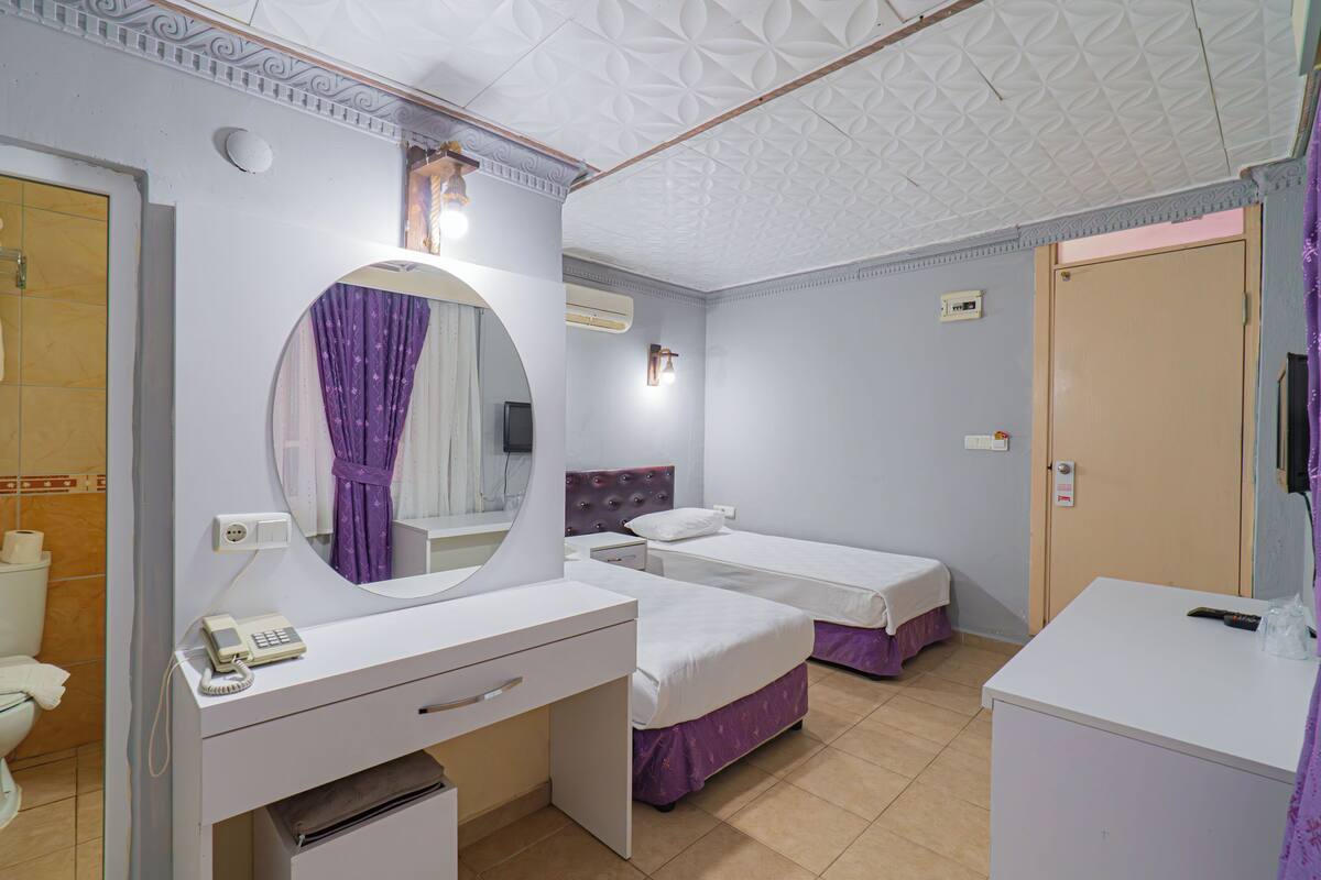 A bedroom with two beds, a bathroom, and a desk with a telephone.
