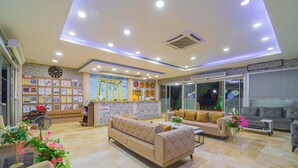 A hotel lobby with a reception desk, a sofa, and a coffee table. - Sayanora Hotel- All Inclusive (Manavgat)