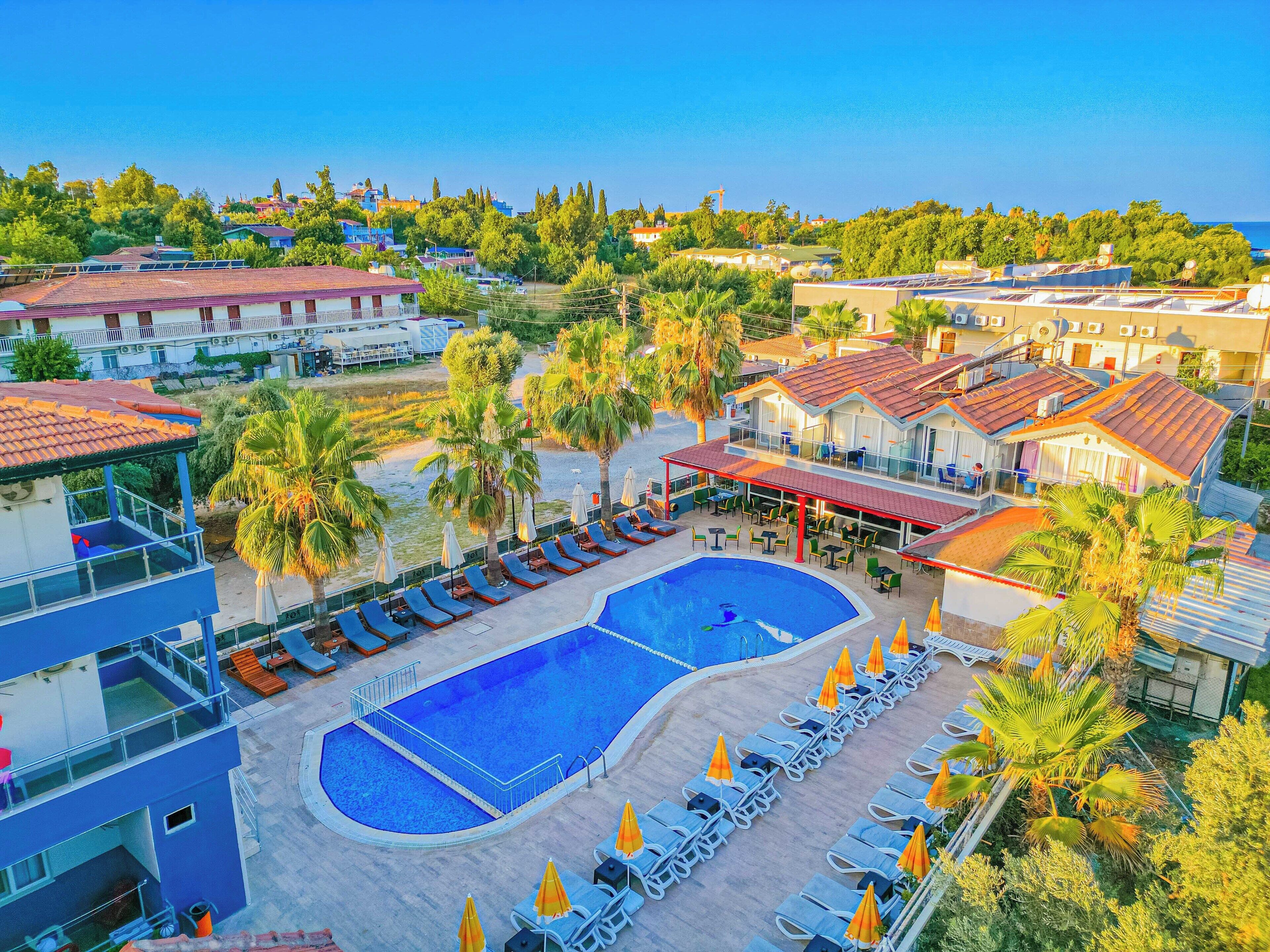 A resort with two swimming pools, sun loungers, and palm trees.