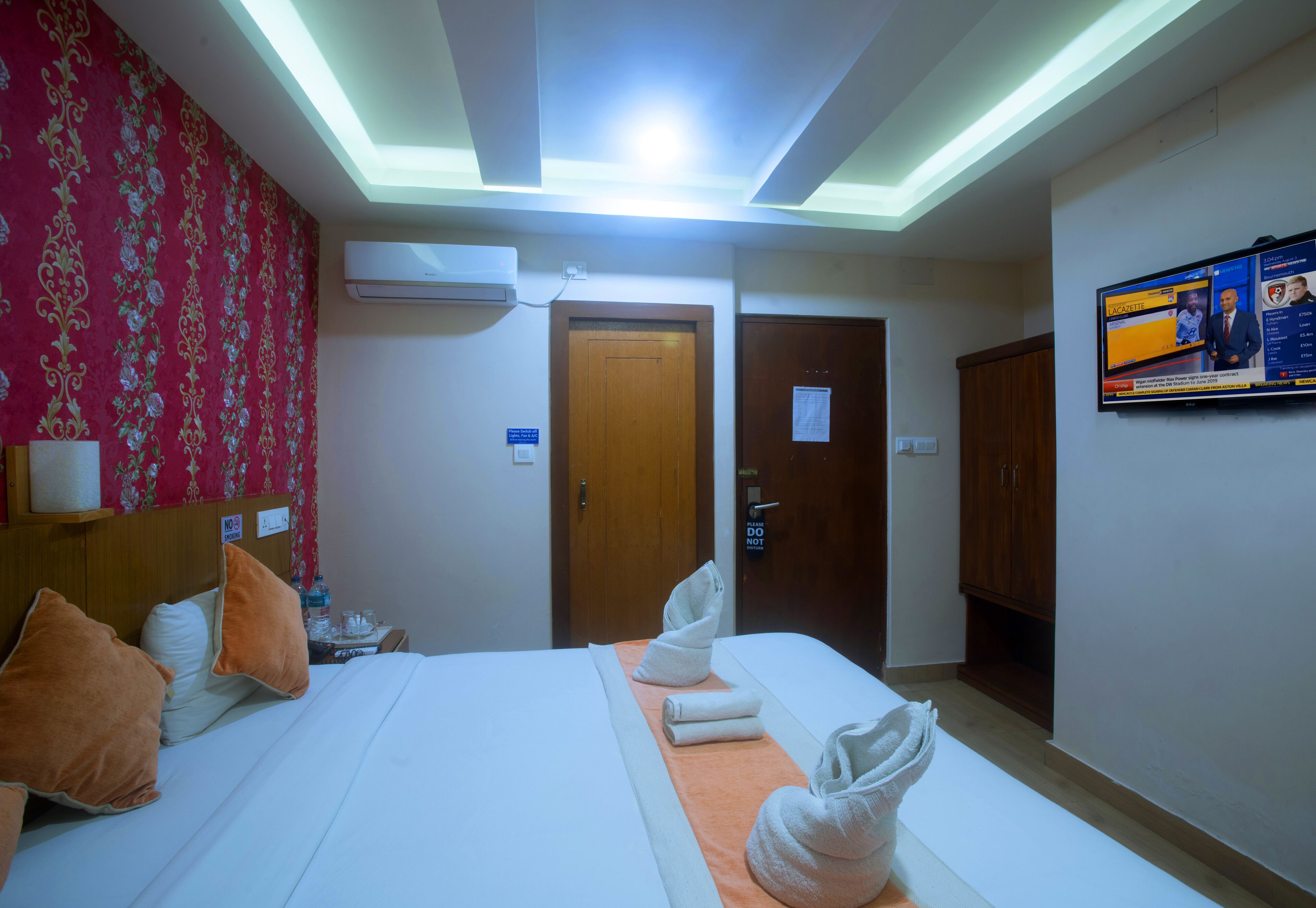 Habitación de hotel con cama, almohadas, televisor y armario de madera.