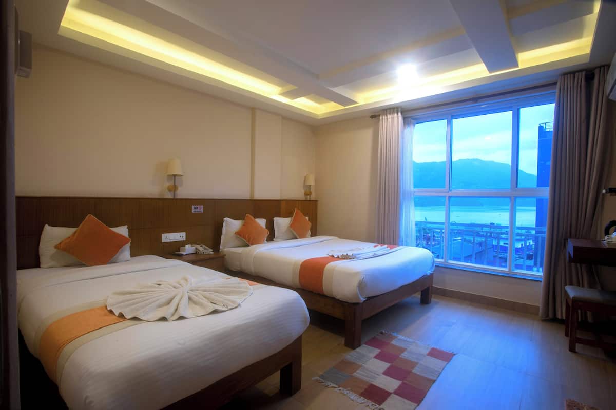 A hotel room with two beds, a large window with a view, and a wooden headboard.