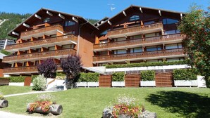 A multi-story hotel with balconies, a ski slope in the background, and well-maintained gardens. - Cozy 2-room flat, 4 guests, near slopes, garage (La Clusaz)