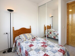 Une chambre à coucher avec un lit en bois, un miroir et une lampe sur pied.