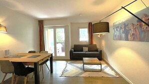 A living room with a sofa, a coffee table, a dining table with chairs, a lamp, and a painting on the wall. - Studio in Chamonix with balcony, 4 people (Chamonix-Mont-Blanc)
