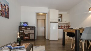 A compact living space with a dining area, kitchenette, and a television displaying a program. - Studio in Chamonix with balcony, 4 people (Chamonix-Mont-Blanc)