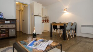 A modern kitchen with white cabinets, a dining table with chairs, and a bottle of wine on a table. - Studio in Chamonix with balcony, 4 people (Chamonix-Mont-Blanc)