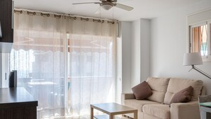 Una sala de estar moderna con un sofá color beige, una mesa de centro de madera y un ventilador de techo.