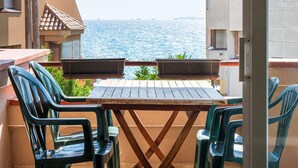 Un balcón con mesa y sillas de madera, con vista al mar.
