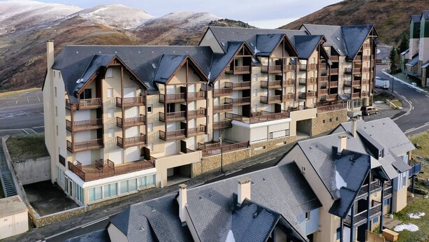 Un hôtel à plusieurs étages, doté de balcons, situé dans une région montagneuse.