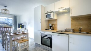 Une cuisine moderne avec des meubles blancs, un four à micro-ondes, une machine à café et un évier.