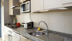 A modern kitchen with a granite countertop, stainless steel sink, microwave, and built-in oven.