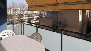 A balcony with a table and chairs, a view of buildings, and a retractable awning.