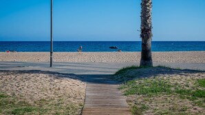 A beach path leading to the sea with a palm tree and a lamp post. - Beachfront Apartment with Terrace and Private Parking (Torredembarra)