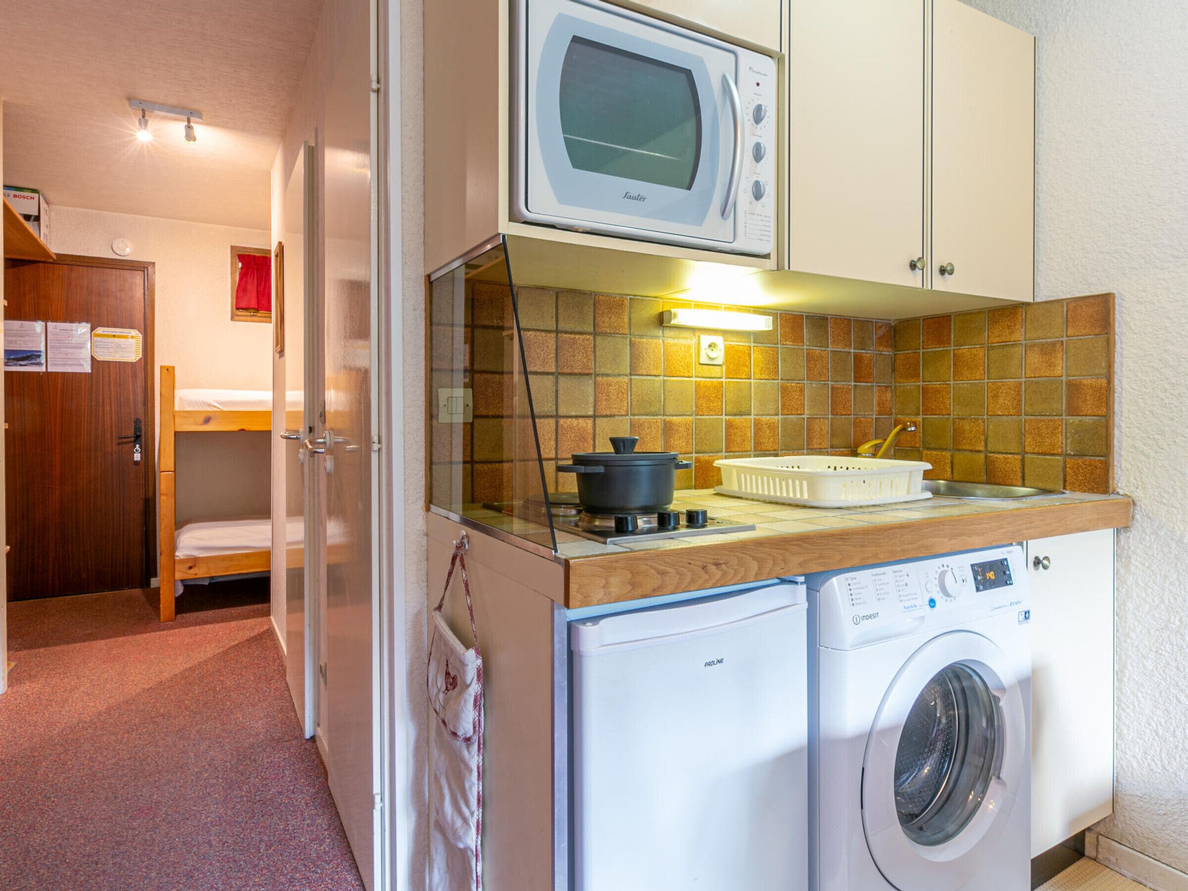A compact kitchenette with a microwave, a washing machine, and a small sink.