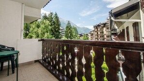 Ein Balkon mit Blick auf Berge und Bäume, mit einem Tisch und Stühlen.