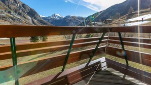 A wooden deck with a view of snow-capped mountains and a clear sky.
