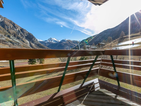 A wooden deck with a view of snow-capped mountains and a clear sky.