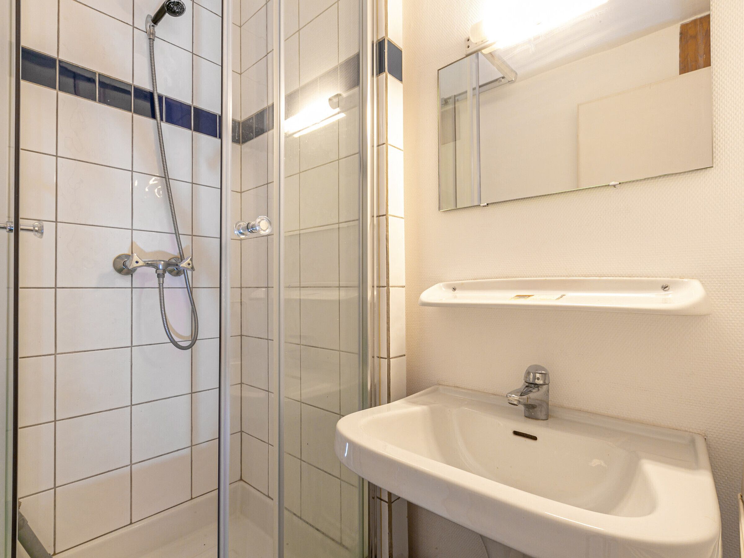 A bathroom with a glass-enclosed shower, a white sink, and a mirror above the sink.