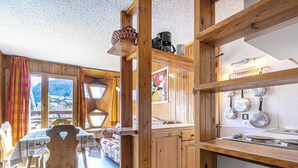 A wooden interior with a dining area, kitchen, and a view of the outside.
