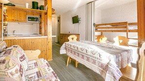 A cozy room with a wooden bunk bed, a small kitchenette with a microwave, and a wooden desk.
