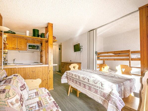 Une chambre confortable avec un lit superposé en bois, une petite kitchenette équipée d’un four à micro-ondes et un bureau en bois.