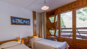 A room with two beds, a painting on the wall, and a view of the outdoors through large windows. - 3-room apartment ski-in ski-out, 6 pers., south, La Daille (Val-d'Isère)