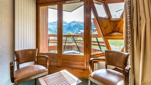 A cozy room with wooden walls and large windows, two leather chairs, and a small table. - 3-room apartment ski-in ski-out, 6 pers., south, La Daille (Val-d'Isère)