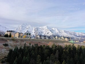 A mountain town with buildings and a forested area in the foreground.