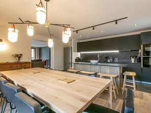 A modern kitchen with a large wooden island, bar stools, and pendant lighting. - Luxurious 5-Room Apartment in Val-d'Isère with Balcony and Mountain Views (Val-d'Isère)