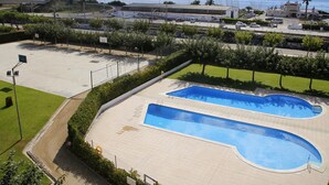 Area piscina con due vasche, circondata da una recinzione e vista sul mare sullo sfondo.