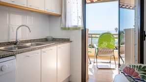 Cucina con mobili bianchi, un piano di lavoro in granito, un lavello in acciaio inossidabile e vista sul balcone.