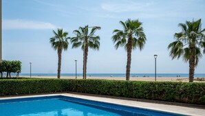 A swimming pool with a view of the beach and palm trees. - Seaside Apartment with Wi-Fi and Parking - Torredembarra (Torredembarra)