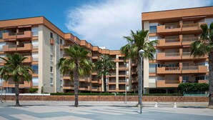 A multi-story residential building with balconies, palm trees, and a paved walkway. - Seaside Apartment with Wi-Fi and Parking - Torredembarra (Torredembarra)