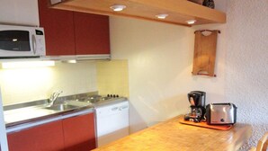 A compact kitchen with a microwave, stove, sink, and a coffee maker on the counter. - Rustic Duplex Apartment with Large South-Facing Terrace Near Val-d'Isère Village (Val-d'Isère)